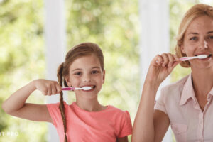 Mother teaching her child how to brush teeth