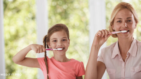 Mother teaching her child how to brush teeth