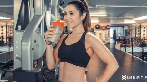 A young fit woman drinks in protein shake in the gym Medifitpro.com